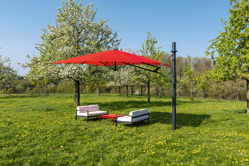 Roter Ampelschirm im Garten mit Gartenmöbel