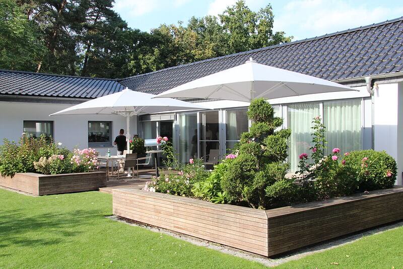 Terrasse eines Einfamilienhauses mit zwei großen weißen Sonnenschirmen