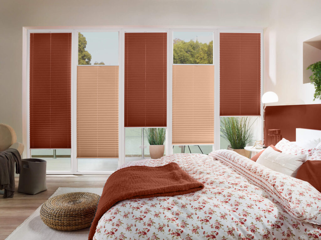 Schlafzimmer mit einer Glasfront, in der zweifarbige Plissees montiert sind.