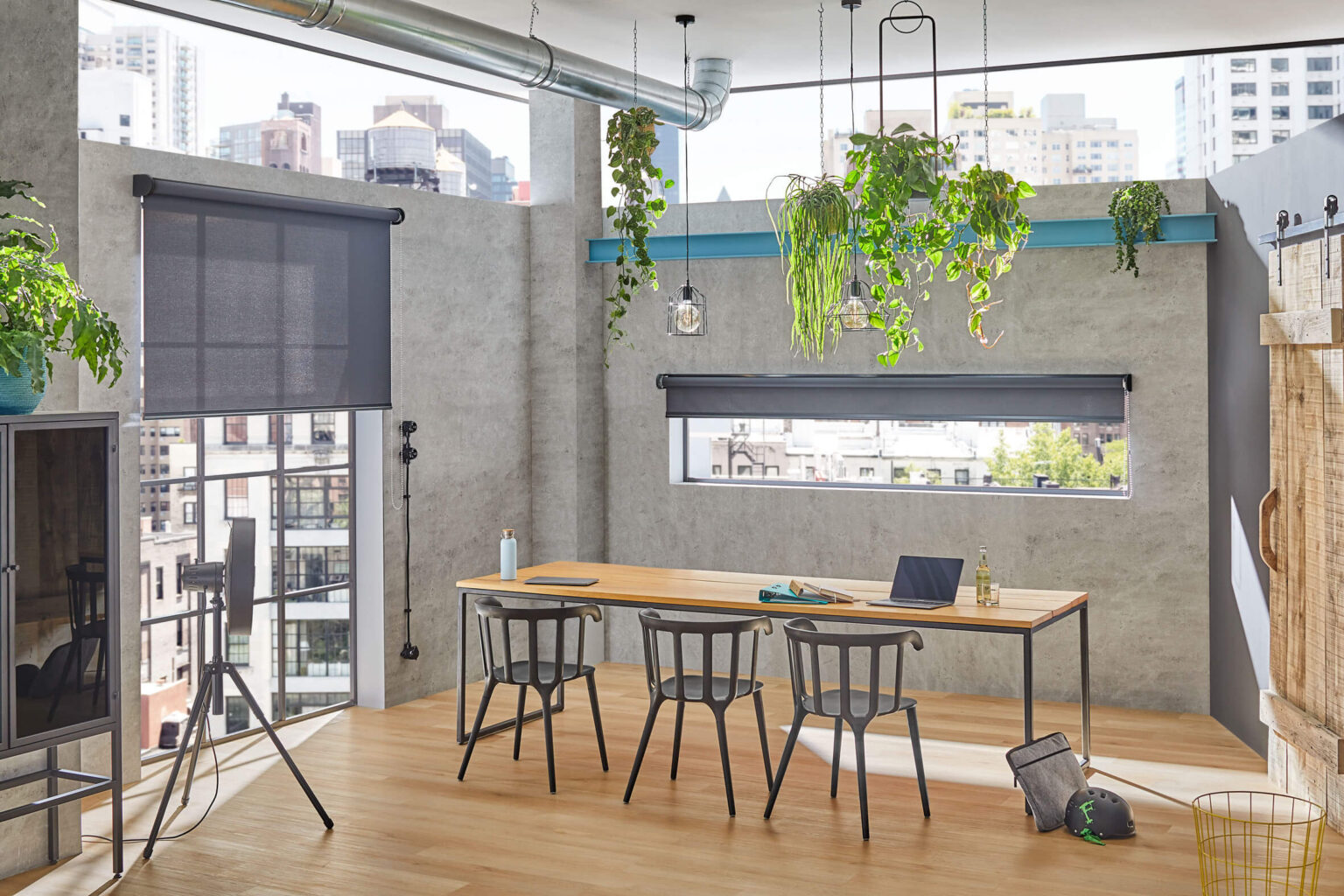 Esszimmer einer Loft Wohnung. An den Fenstern sind dunkle Rollos montiert.