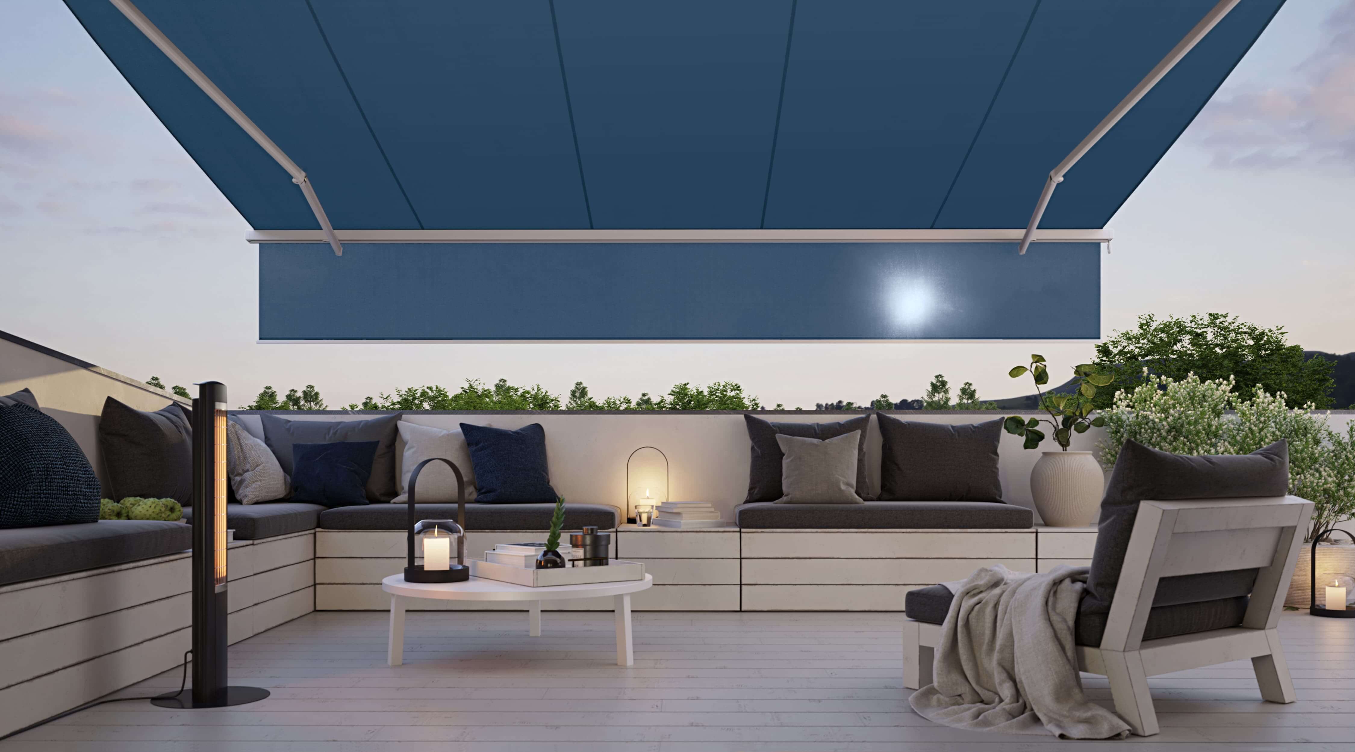 Terrasse mit ausgefahrene Markise. An der Markise ist der Schatten plus heruntergefahren, um die tief stehende Sonne abzuhalten. Die Markise ist weiß mit einem blauen Tuch.