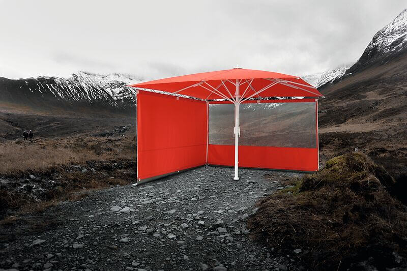 Roter Sonnenschirm in einer Berglandschaft mit Seitenwänden