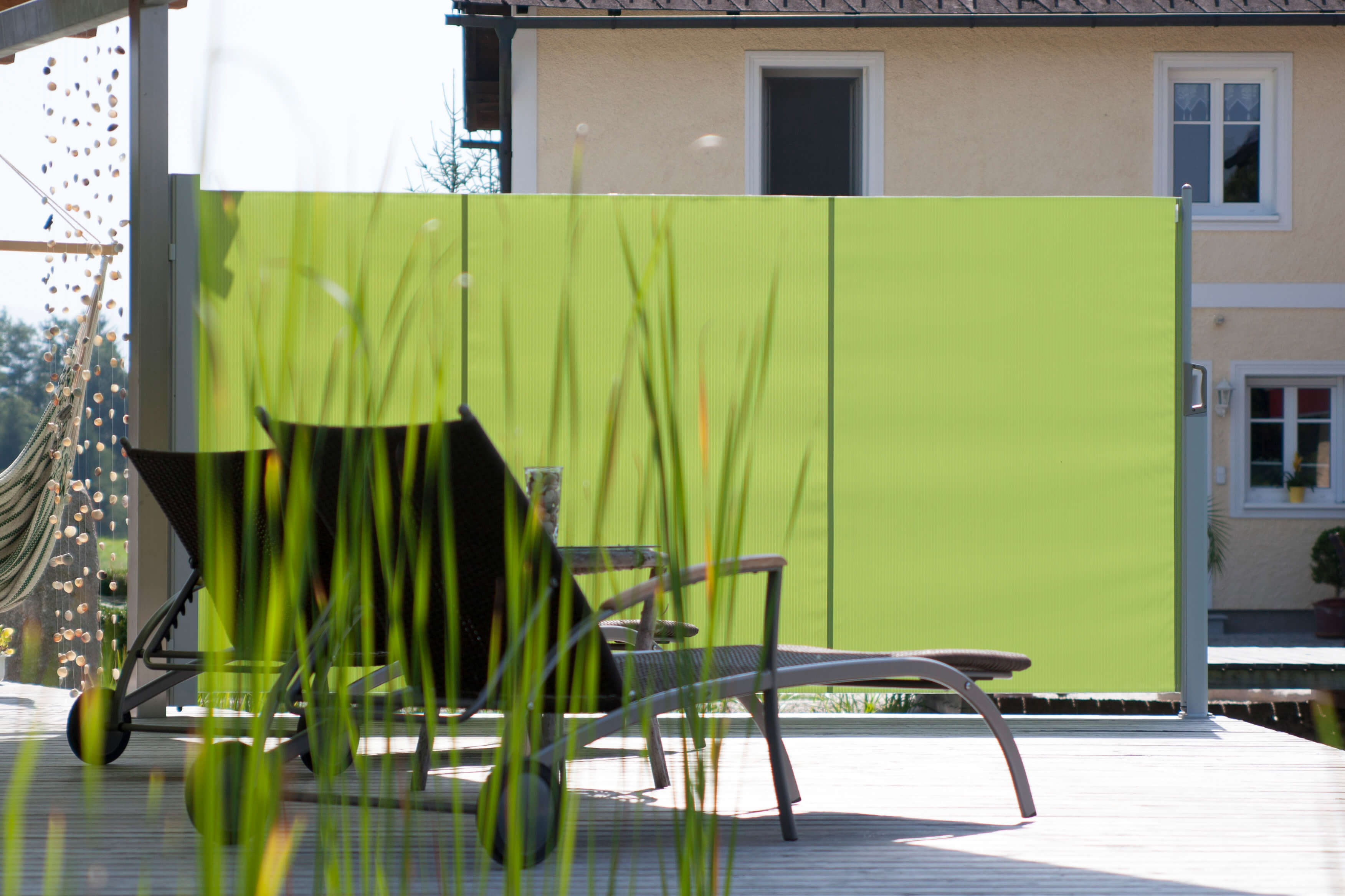 Grüne Seitenmarkise an einer Terrasse mit Liegestuhl