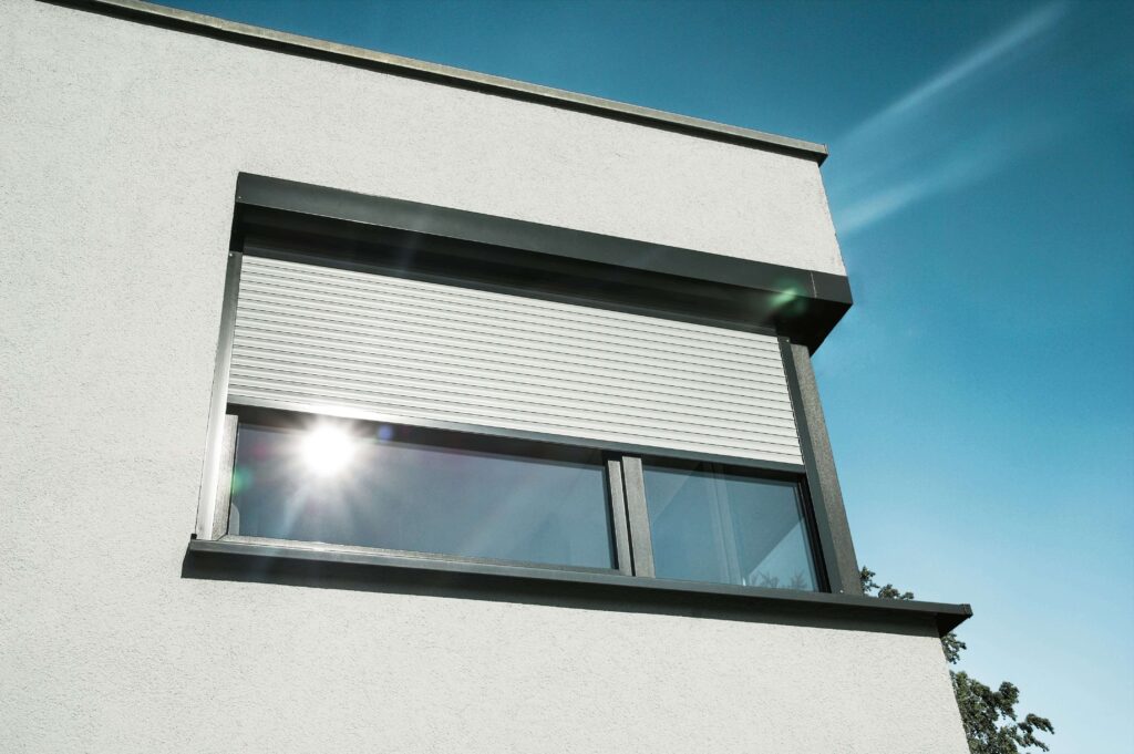 Ansicht eines Hauses von außen mit einem Eckfenster, an dem ein Rollladen vorgebaut ist